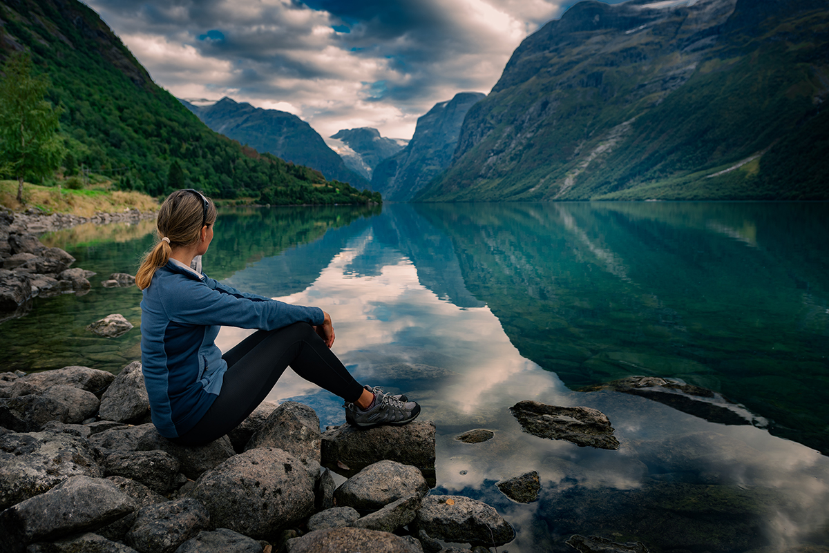ourist admires Lovatnet Lake Norway Serene Norwegian fjord with crystal-clear waters surrounded by towering mountains