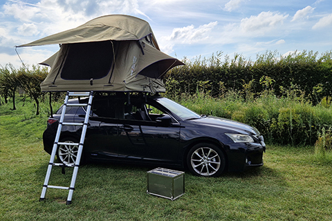 Car with rooftop tent in green surroundings