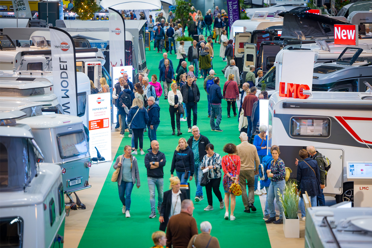 Full aisles at Camping &amp; Caravan Jaarbeurs. Visitors view caravans and motorhomes.